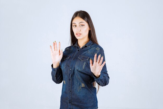 Jeune femme en chemise en jean essayant d'empêcher et d'arrêter quelque chose