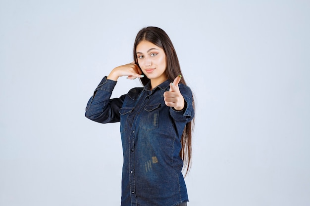 Jeune femme en chemise en jean montrant l'indicatif d'appel