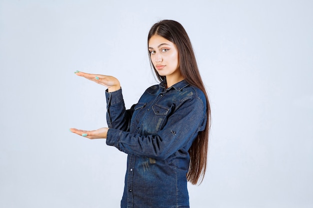 Jeune femme en chemise en jean montrant les mesures d'un produit