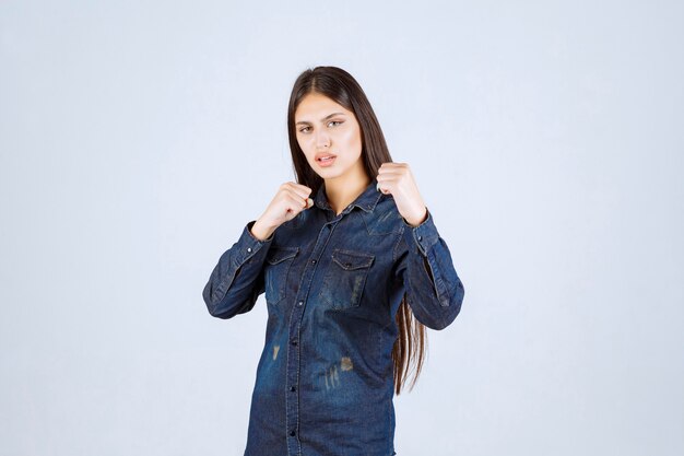 Jeune femme en chemise en jean montrant ses muscles du bras