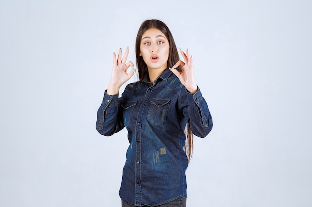 Jeune femme en chemise en jean montrant un signe de main positif