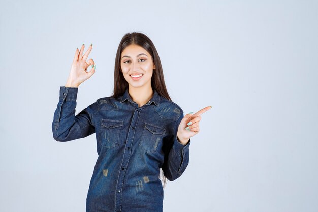 Jeune femme en chemise en jean pointant vers le côté droit