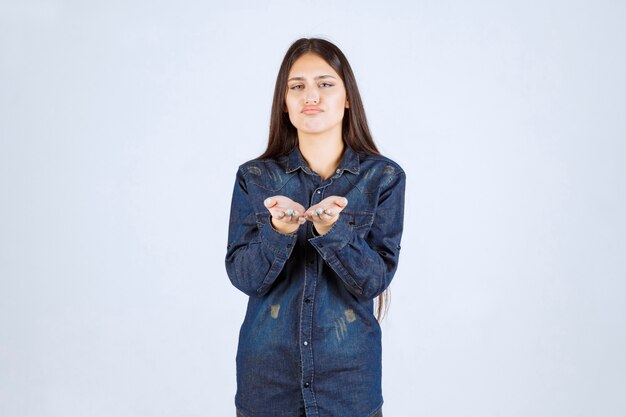 Jeune femme en chemise en jean pointant vers la personne en face d'elle