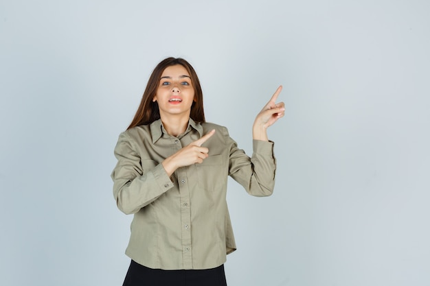 Jeune femme en chemise, jupe pointant vers le coin supérieur droit et à la gaieté, vue de face.