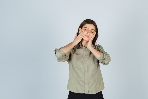 Jeune femme en chemise, jupe tenant les mains sur les joues et à la détente