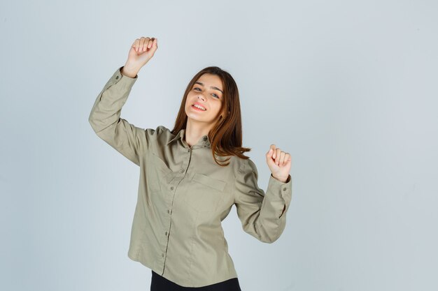 Jeune femme en chemise montrant le geste du gagnant et à la chance