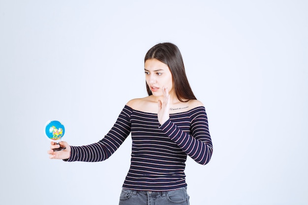 Jeune Femme En Chemise Rayée Tenant Un Mini Globe Et Veut L'arrêter