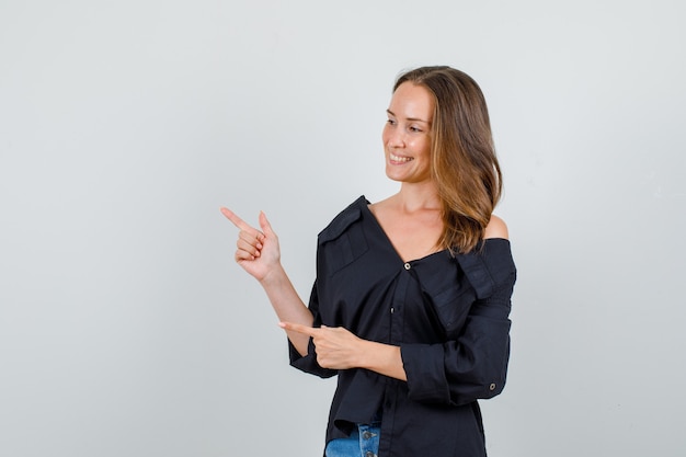 Jeune femme en chemise, short pointant les doigts et à la joyeuse