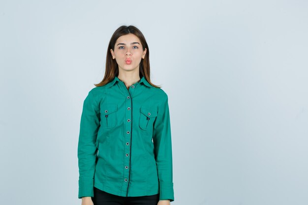 Jeune femme en chemise verte boudant les lèvres et à la jolie vue de face.