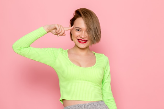 jeune femme en chemise verte et jupe grise souriant posant