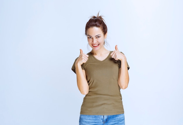 Jeune femme en chemise verte montrant un signe de plaisir