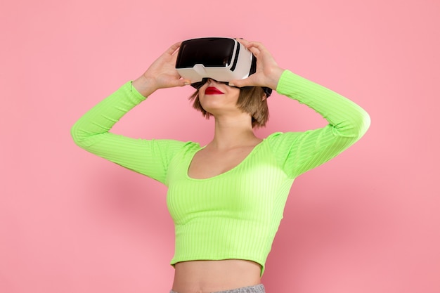 Jeune femme en chemise verte et pantalon gris essayant le jeu de réalité virtuelle