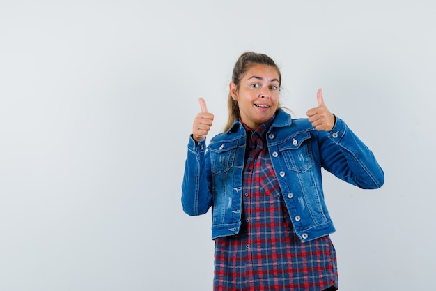 Jeune femme en chemise, veste montrant le double pouce vers le haut et à la vue de face, confiant.