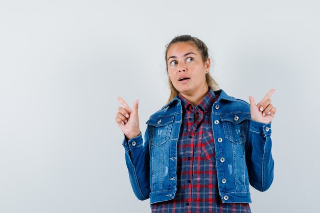 Jeune femme en chemise, veste pointant vers le haut et à l'espoir, vue de face.