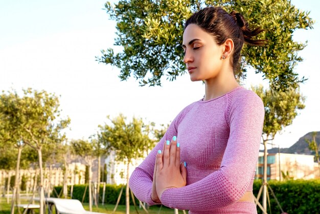 Jeune femme en chemise violette et pantalon sur l'herbe pendant la journée à l'intérieur de Green Park méditant et faisant du yoga dans différentes poses