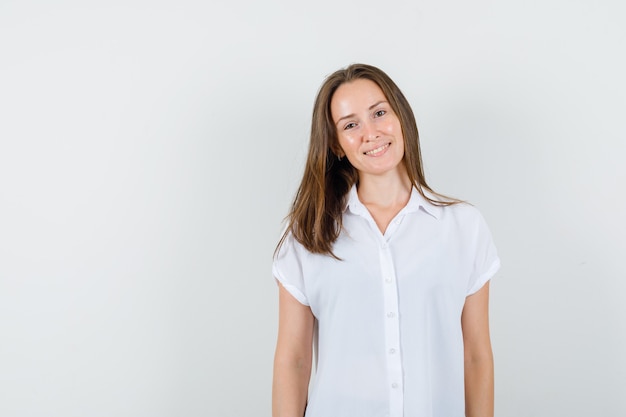 Jeune femme en chemisier blanc debout tout en souriant et à la jolie