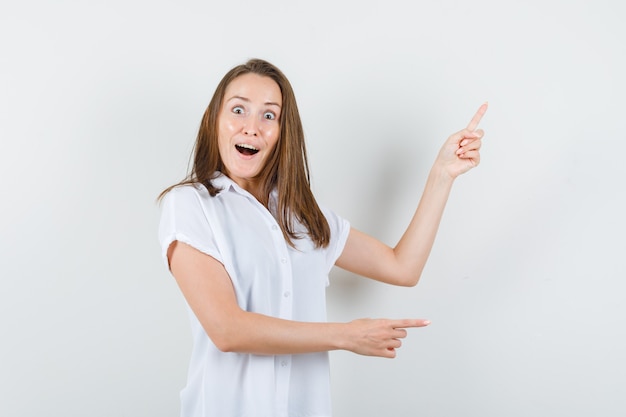 Jeune Femme En Chemisier Blanc Pointant De Côté Et à La Surprise