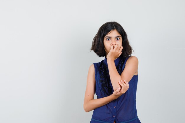 Jeune femme en chemisier couvrant la bouche avec sa main et à la peur.