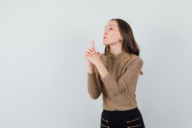 Jeune femme en chemisier, jupe montrant le geste du pistolet et à la vue de face, confiant. espace pour le texte