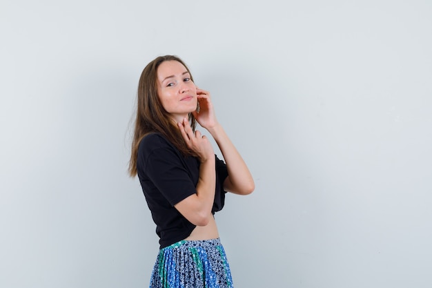 Jeune femme en chemisier, jupe posant en position debout et à la délicate