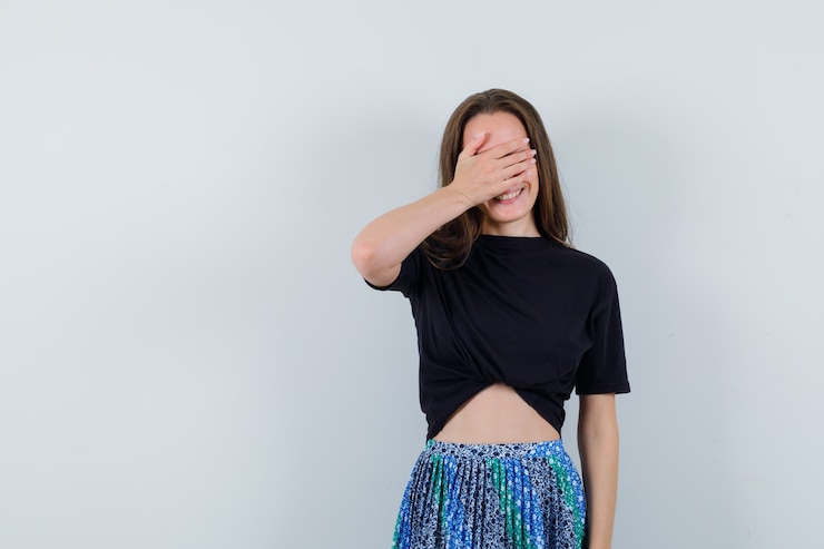 Photo gratuit jeune femme en chemisier, jupe tenant la main sur les yeux et à la jolly