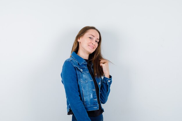 Jeune femme en chemisier posant debout et semblant délicate, vue de face.