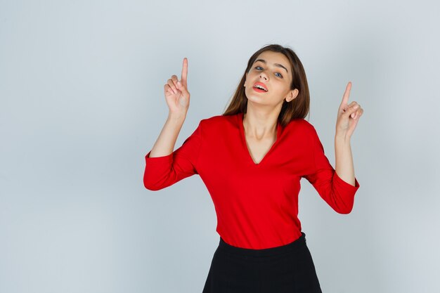 Jeune femme en chemisier rouge, jupe pointant vers le haut et à la magnifique