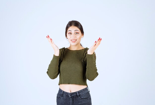 Jeune femme en chemisier vert à la recherche de réponses sur le mur blanc