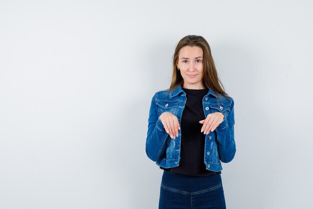 Jeune femme en chemisier, veste gardant les mains comme des pattes sur la poitrine et belle vue de face.