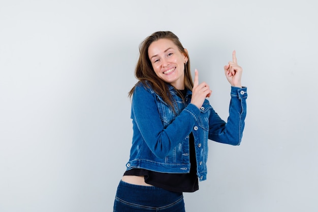 Jeune femme en chemisier, veste pointant vers le haut et à la gaieté, vue de face.