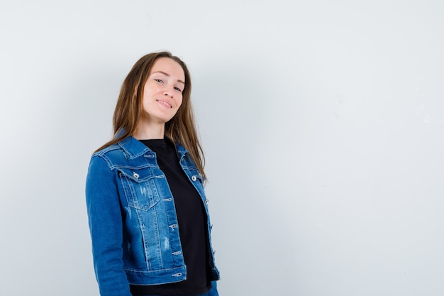 Jeune femme en chemisier, veste regardant la caméra et l'air confiant, vue de face.