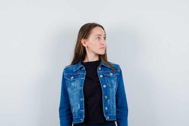 Jeune femme en chemisier, veste regardant de côté et ayant l'air calme, vue de face.