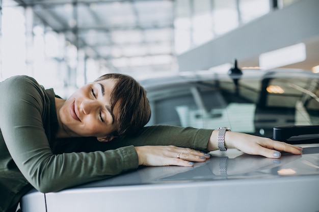 Photo gratuite jeune femme choosimng une voiture dans une salle d'exposition de voiture