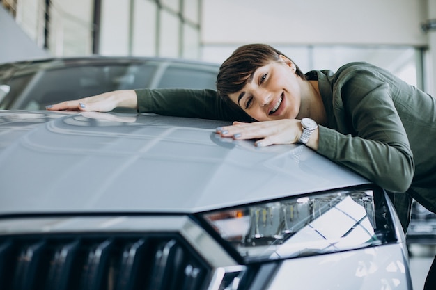 Jeune femme choosimng une voiture dans une salle d'exposition de voiture