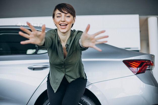 Jeune femme choosimng une voiture dans une salle d'exposition de voiture