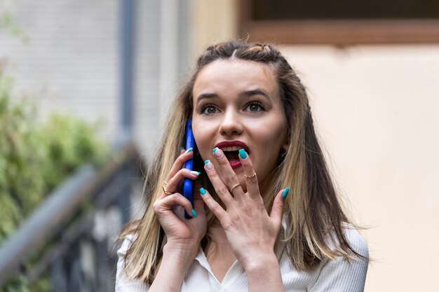 Jeune femme choquée debout dans la rue en parlant au téléphone