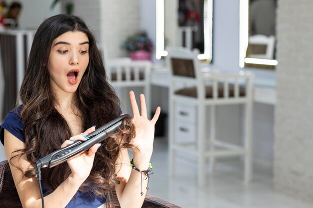 Une jeune femme choquée s'est brûlé le doigt avec un sèche-cheveux Photo de haute qualité