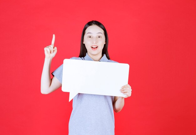 Jeune femme choquée tenant une planche ida et pointant plus finement