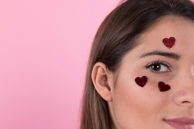 Photo gratuite jeune femme avec coeurs d'ornement sur le visage