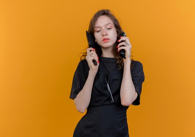 jeune femme, coiffeur, porter, uniforme, tenue, tondeuses cheveux, et, peigne, près, tête, regarder bas