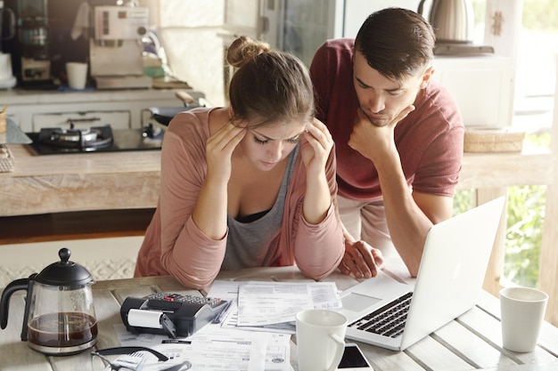 Photo gratuite jeune femme en colère se sentant déprimée, serrant les tempes, essayant de résoudre des problèmes financiers