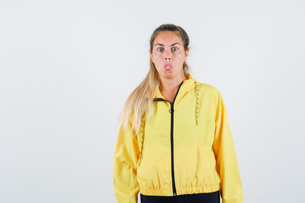 Jeune femme collant la langue en imperméable jaune et à la bizarre