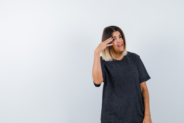 Jeune femme comptant tout en posant en robe polo et à la joyeuse vue de face.