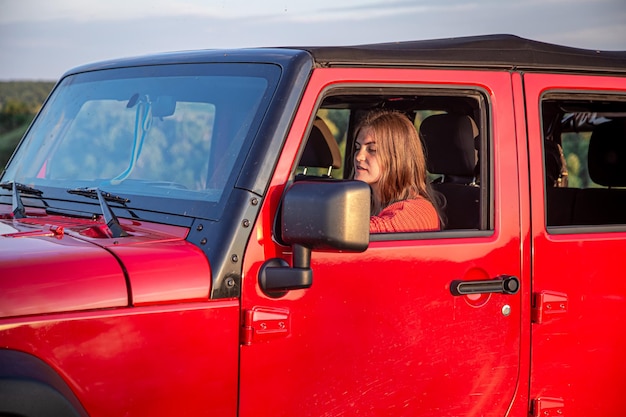 Photo gratuite une jeune femme conduisant un suv à la campagne