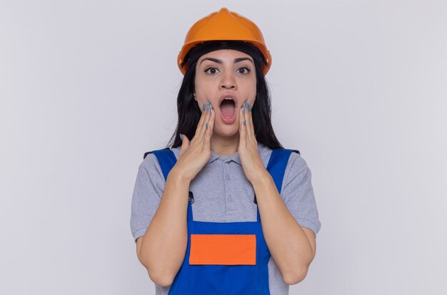Jeune femme constructeur en uniforme de construction et casque de sécurité regardant la caméra