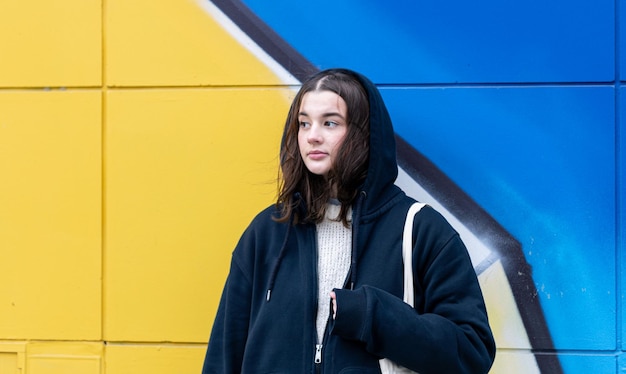 Une jeune femme contre un mur jaune bleu graffiti urbain