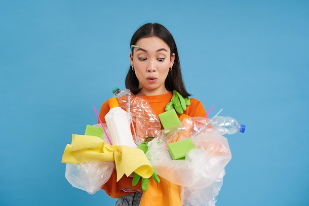 Photo gratuite jeune femme coréenne regardant choquée par les déchets plastiques tenant des ordures pour le recyclage avec emo surpris