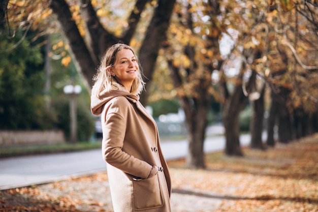 Jeune femme en costume beige à l'extérieur dans un parc en automne