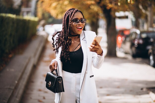 Jeune femme en costume blanc à l'aide de téléphone