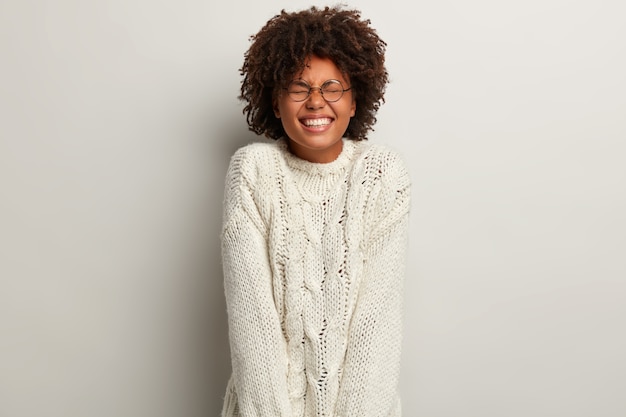 Jeune femme avec coupe de cheveux afro portant un pull blanc